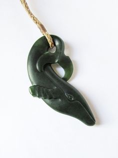 a green ceramic alligator ornament hanging from a rope on a white wall with no background