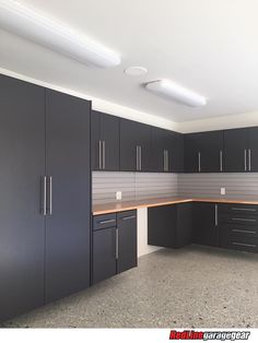 an empty kitchen with black cabinets and counter tops