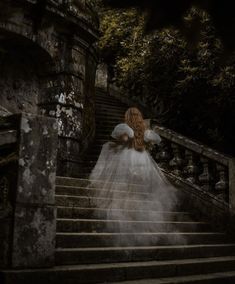 a woman in a white dress walking down some stairs with her back to the camera