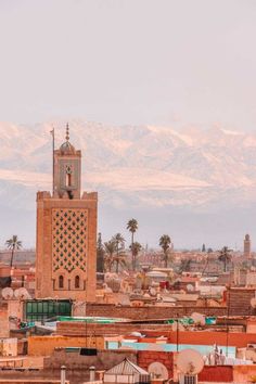 a tall clock tower towering over a city filled with lots of buildings and mountains in the background