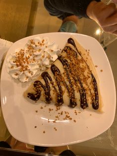 a piece of cheesecake on a plate with whipped cream and chocolate drizzle