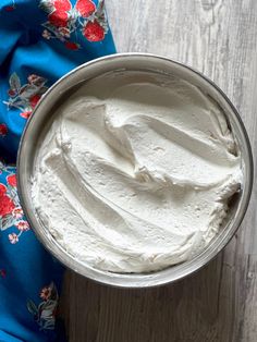 a metal bowl filled with whipped cream on top of a wooden table