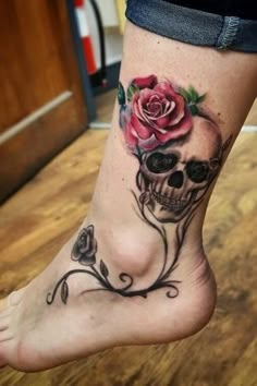 a woman's foot with a skull and rose tattoo on it