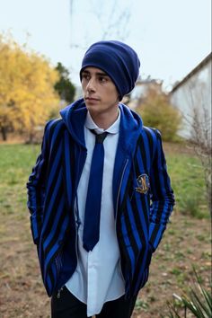 a young man wearing a blue tie and striped jacket with a white shirt underneath it