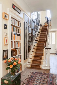 there is a staircase in the house with many pictures on the wall and rugs