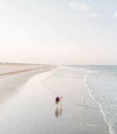 a man walking along the beach with his dog