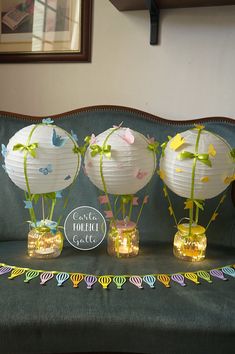 three paper lanterns sitting on top of a green couch