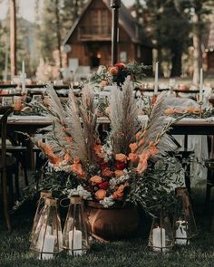 an outdoor table set up with candles and flowers in vases on the grass for a wedding reception