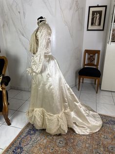 a dress on display in a room next to a chair and table with an ornate rug