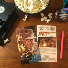 a table topped with a bowl of popcorn and a movie ticket