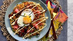 a white plate topped with rice covered in toppings and an egg sitting on top of it