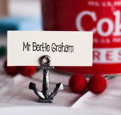 a small metal anchor sitting on top of a table next to a red cup and saucer