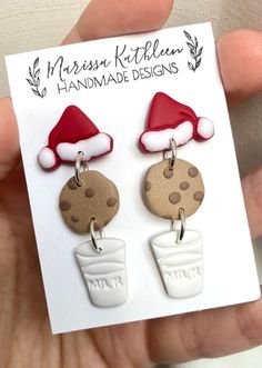 a pair of earrings with santa hats and cookies hanging from it's earwires