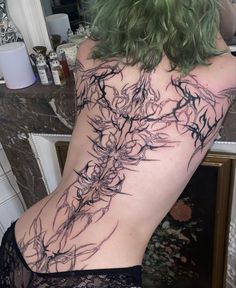 the back of a woman's body with black and grey tattoos on her stomach