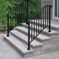 a set of stairs leading up to the front door of a house with stone steps and handrails