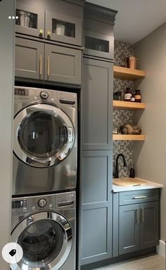 a washer and dryer in a small room with shelves on the wall behind them