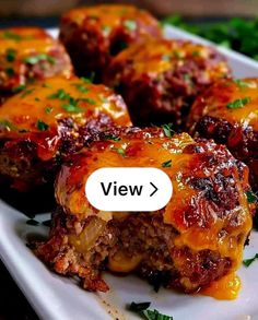 a white plate topped with meatballs covered in sauce and parsley next to a green leafy garnish