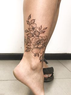 a woman's leg with flowers on it and her bare foot in the foreground