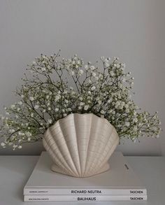 a white vase filled with flowers sitting on top of two books