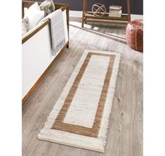 a white and brown rug on top of a wooden floor next to a chair in a living room