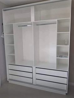 a white closet with two doors and drawers in the middle of an empty room next to a toilet