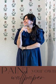 a woman standing in front of a wallpaper with the words paint your own wallpaper