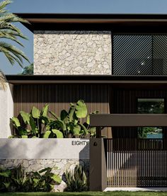 the entrance to an elegant home with stone and wood accents, along with palm trees