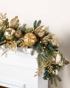 a decorated fireplace mantel with gold ornaments and greenery