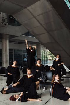 a group of people in graduation gowns sitting on the ground