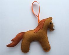 a brown felt horse ornament hanging on a white background with an orange ribbon