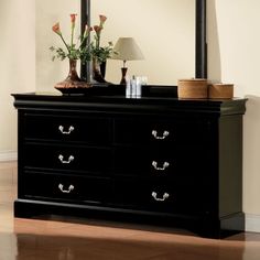 a black dresser with a mirror on top of it next to a vase filled with flowers