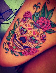 a woman's thigh with a colorful sugar skull and flowers on the side,