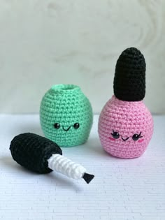 three crocheted objects are sitting on a white surface, one has eyes and the other has a black nose