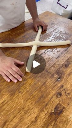 a person is making an object out of dough and rolling it on a wooden table