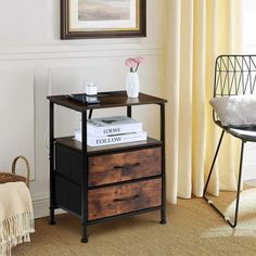 a small table with two drawers on it in front of a window and a chair