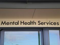 a sign that says mental health services on the side of a building with large windows