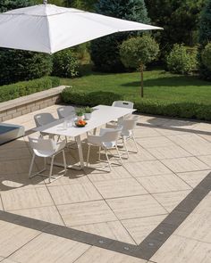 an outdoor dining table with white chairs and an umbrella