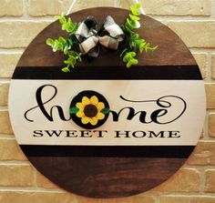 a wooden sign that says home sweet home with a sunflower and bow on it