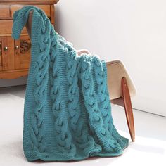 a blue blanket sitting on top of a wooden chair next to a dresser and cabinet