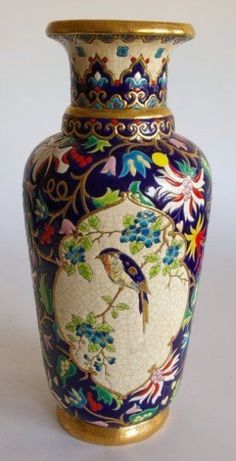 an ornate vase with a bird painted on the front and sides, sitting against a white background