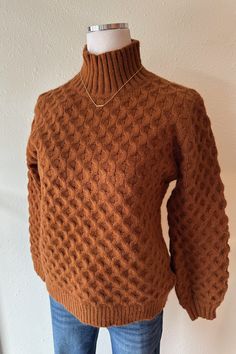 a brown turtle neck sweater on a mannequin's dummy head, wearing jeans and a necklace