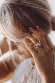 a woman is holding her hand up to her face while wearing a wedding band and diamond ring