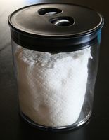 a glass container filled with white flour on top of a black table next to a window