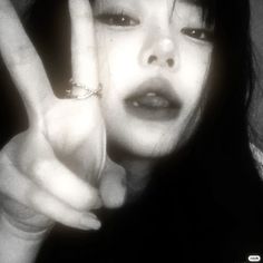 a young woman making the peace sign with her fingers in front of her face and wearing a ring