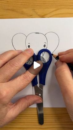 someone cutting out an elephant cutout with scissors on top of a piece of paper