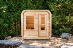 a wooden sauna in the middle of some rocks and trees with its doors open