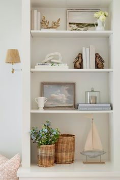 a white book shelf filled with books and vases