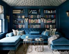 an image of a living room with bookshelves on the wall and blue couches