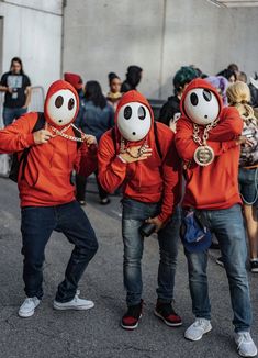 three people in red hoodies with faces painted on them