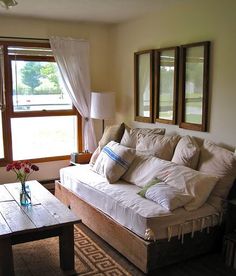 a living room with a couch, coffee table and two mirrors on the wall above it